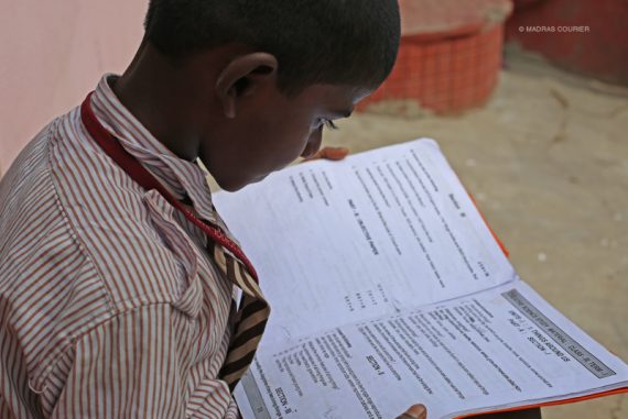 child_reading_textbook_madras_courier